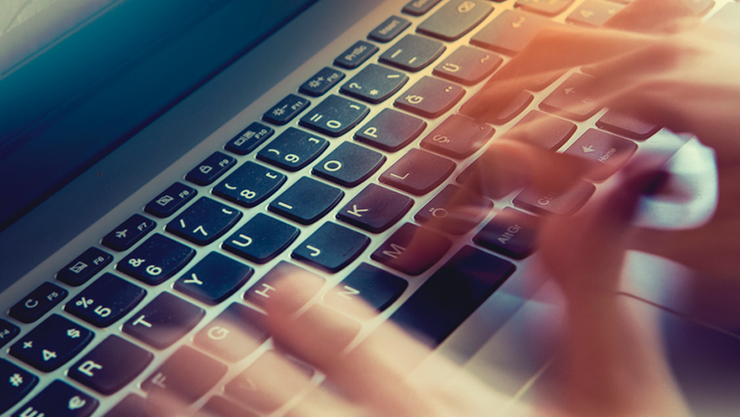 © iStock/UfukSaracoglu unscharfe Hände tippen auf Laptop-Tastatur
