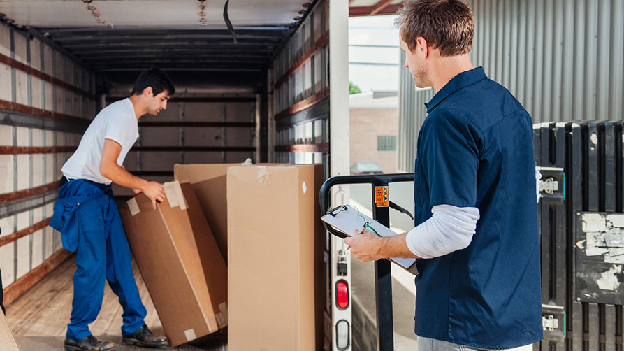© iStock | Camrocker Zwei Arbeiter entladen Pakete aus LKW.