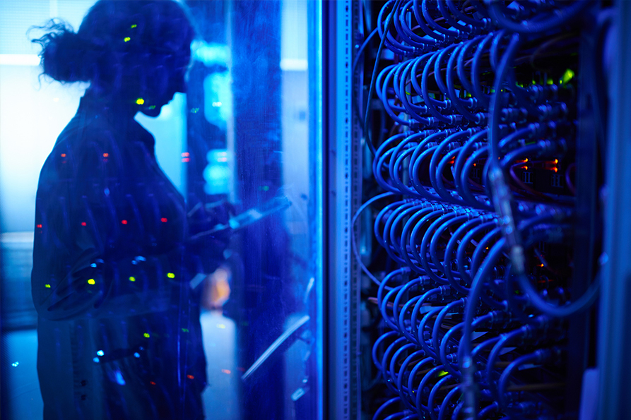 © iStock/mediaphotos Female employee in a server room is reflected in a plexiglass pane