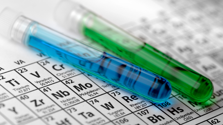 © iStock | peepo Two sealed test tubes with green and blue liquid lie on a periodic table.