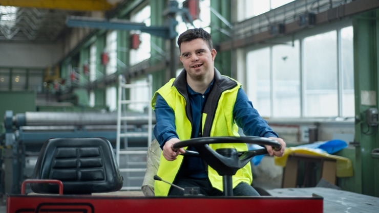 © iStock | Halfpoint A young man with Down syndrome works in an industrial factory, drives a work machine, concept of social integration